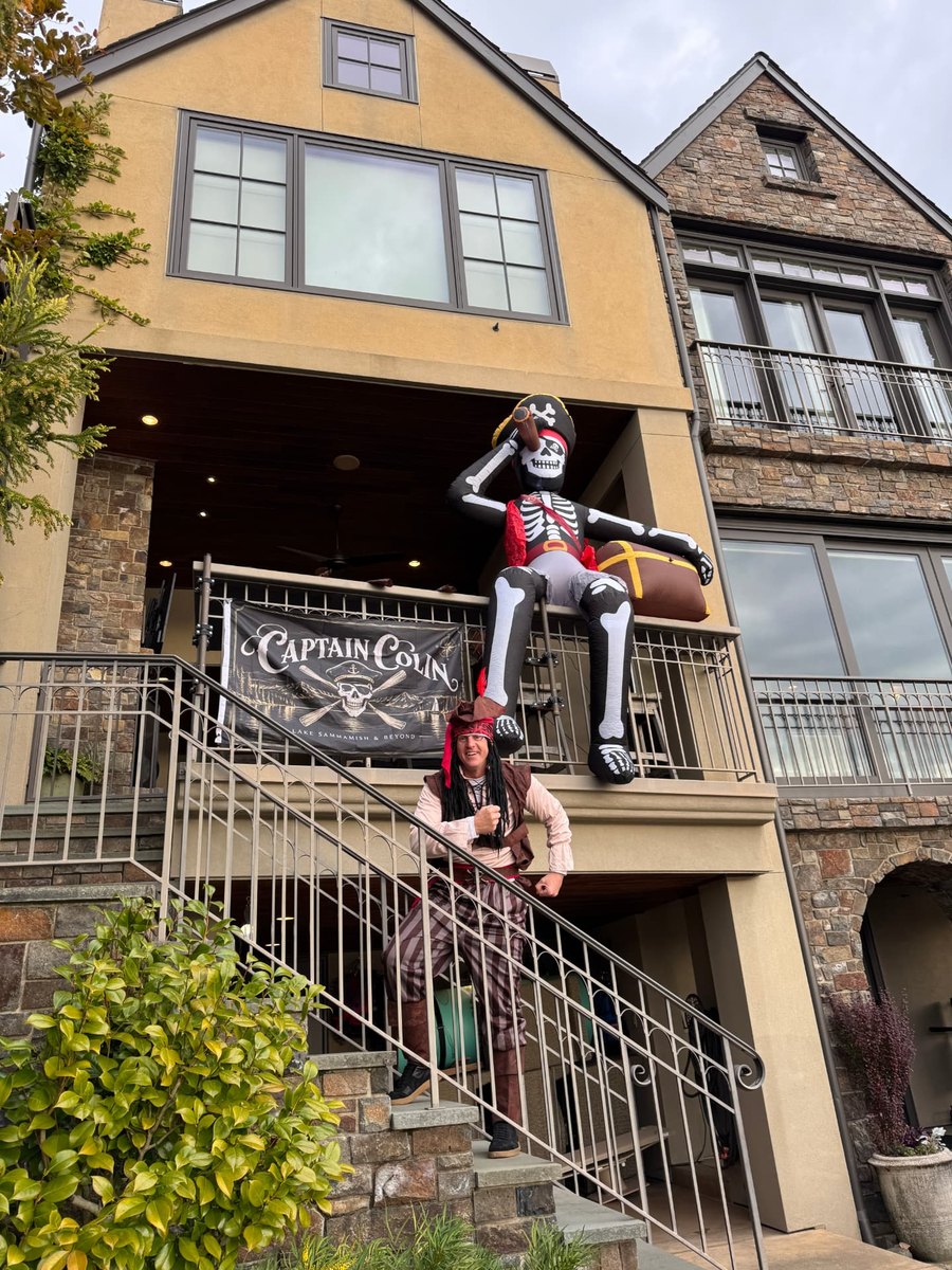 A waterfront home decorated for Dock or Treat with a Captain Colin banner and a pirate on the stairs