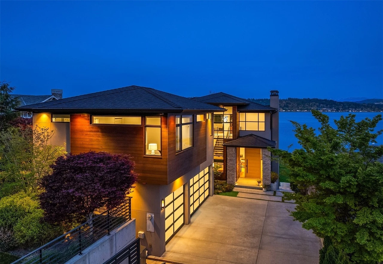 Modern Lake Sammamish home at dusk with glowing windows and the lake beyond