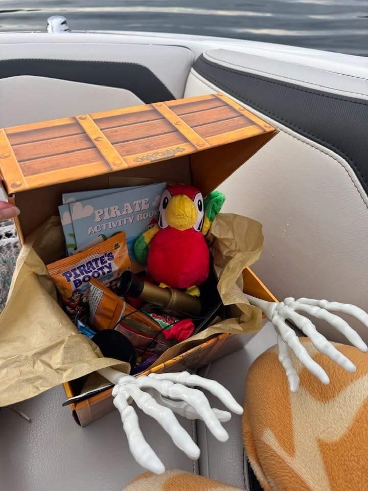 An open treasure chest filled with candy, a plush parrot and a pirate activity book
