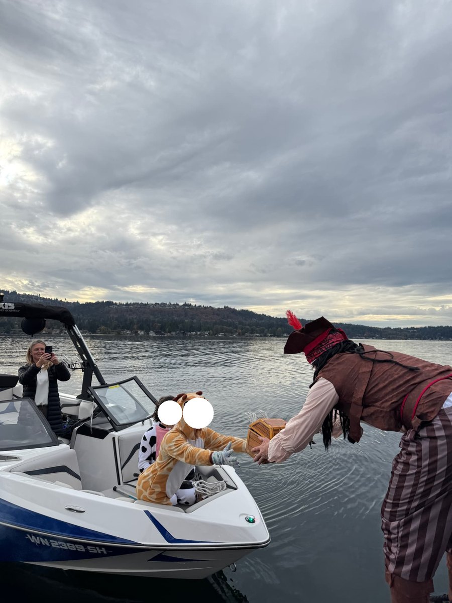 Captain Colin handing a treasure chest of treats to kids in costume at the dock
